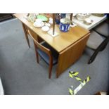 A vintage teak desk, having two drawers and side flap on turned legs, with a single teak chair by