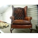 A red leather wingback armchair, having deep buttoned back, on cabriole legs