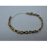 9ct yellow bracelet, each link in the form of a bow, with a central garnet, marked 375, with