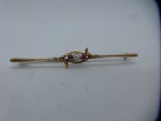 Unmarked yellow metal bar brooch with central diamond flanked with rubies, unmarked, pin slightly