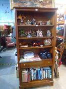 A dark cherrywood bookcase with a central drawer