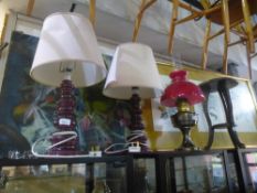 Two red ceramic lamps with shades, oil lamp with red shade and a wooden carved stool