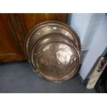 Three Eastern copper trays of various sizes with engraved decoration, the largest 81 cms