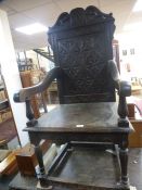 An old carved oak armchair with solid back and a similar oak two drawer side table, 106cms
