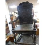 An old carved oak armchair with solid back and a similar oak two drawer side table, 106cms