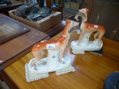 A pair of Staffordshire greyhounds holding rabbits, 28cms