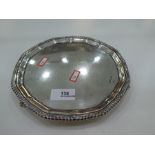 A heavy silver tray on trefoil paw feet of circular form with decorative border.  Shaped rim, hallma