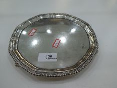 A heavy silver tray on trefoil paw feet of circular form with decorative border.  Shaped rim, hallma