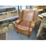 A modern tan leather reclining wingback armchair