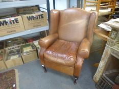 A modern tan leather reclining wingback armchair