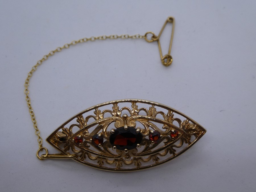 9ct Yellow gold oval brooch set with faceted garnets, marked 375 on pin, with safety chain, approx..