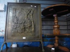 A brass firescreen decorated figures and a small lamp table