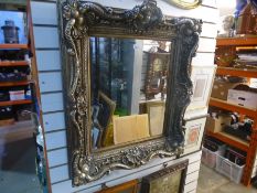 A modern ornate wall mirror having bevelled glass