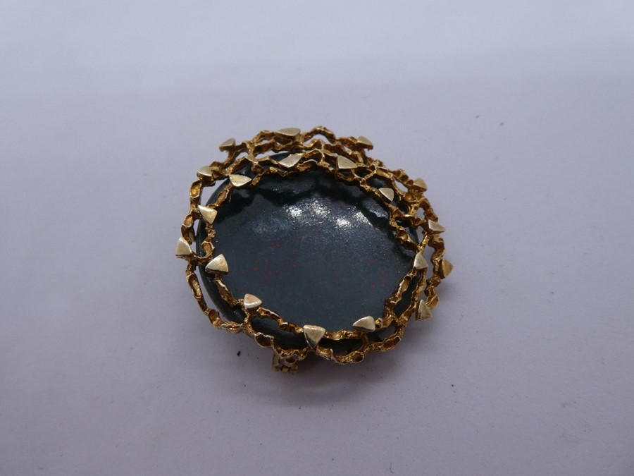 A modernist circular brooch, with polished hardstone in 9ct yellow gold mount, marked 375