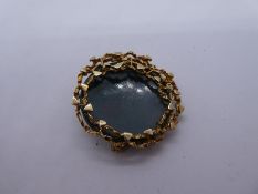 A modernist circular brooch, with polished hardstone in 9ct yellow gold mount, marked 375