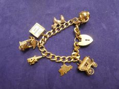 9ct yellow gold charm bracelet with heart shaped padlock clasp marked 375, hung with 7 9ct yellow go