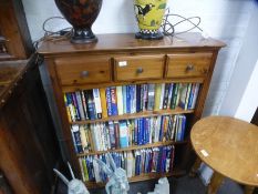 A modern pine bookcase having three drawers and a small circular pine table