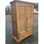 A Victorian pitch pine wardrobe with moulded cornice above panelled doors enclosing hanging space