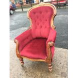 A Victorian button upholstered armchair, the back with carved crest on moulded scrolled frame,