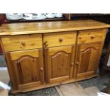 A pine dresser base with three frieze drawers above arched fielded panelled cupboards on a shaped