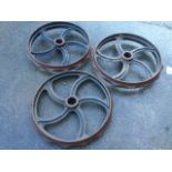 Three cast iron wheels with rippled rims, each having five scroll cast spokes around tubular