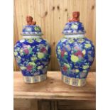 A pair of ovoid Chinese porcelain jars & covers, decorated with prunus blossom flowers on blue