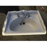 An Edwardian hand basin fitted with three taps, having shell moulded soap trays and moulded rim. (