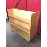 A Gresswell beech book trolley, the rectangular cabinet with three shelves each side, raised on