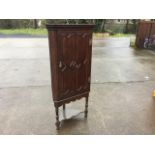 An oak corner cupboard with moulded cornice above a brass H-hinged door with applied panelled