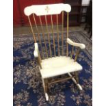 A painted rocking chair with spindle back and shaped arms above a solid seat, raised on ring-