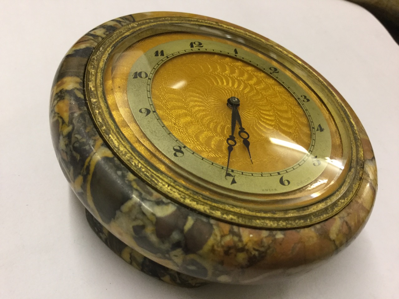 A Swiss made 1930s eight-day table clock, the circular moulded marble case on four feet mounted with
