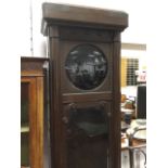 A 1930s 7ft oak longcase clock case, having rounded fluted cornice above a glazed door with