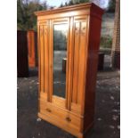 A late Victorian satin walnut wardrobe, with moulded cornice above a central bevelled mirror door