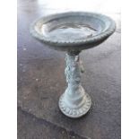 A composition stone birdbath, the circular bowl with leaf moulded rim supported on a floral leaf