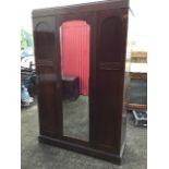 A stained wardrobe with caddy top and central arched bevelled mirror door flanked by panels with