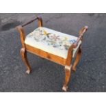 A walnut piano stool with tapestry woolwork upholstered seat flanked by turned handles, raised on