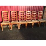 A set of six hardwood ladderback dining chairs, with arched rails above rush seats, raised on square