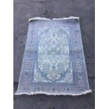 A pale oriental silk woven rug, with scalloped oval field having central floral medallion flanked by