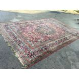 A oriental floral carpet woven with central scalloped medallion and spandrels in red field, framed