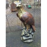 A painted composition stone eagle mounted on rocky base. (26in)