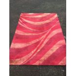 A contemporary hand-tufted wool pile Indian rug of red/pink whirled design. (89in x 63in)