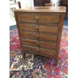 An Edwardian music cabinet with rectangular moulded top above five drop-down drawers, raised on