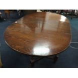 An oak dining table with two rounded drop-leaves, raised on baluster turned legs joined by
