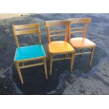 A pair of 1960s beech chairs with rounded backs above brightly coloured pad seats, raised on