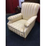 An upholstered armchair with padded back and arms framing the long sprung seat, raised on turned