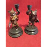 A pair of cold painted bronze bear & fox candlesticks, the fox with dice & cards, and bear with