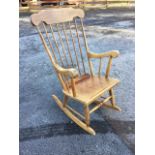 A spindleback rocking chair with shaped back rail and splayed arms above a ply seat, raised on