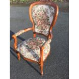 A Victorian style floral tapestry upholstered armchair, with foliate scroll carved crest above a