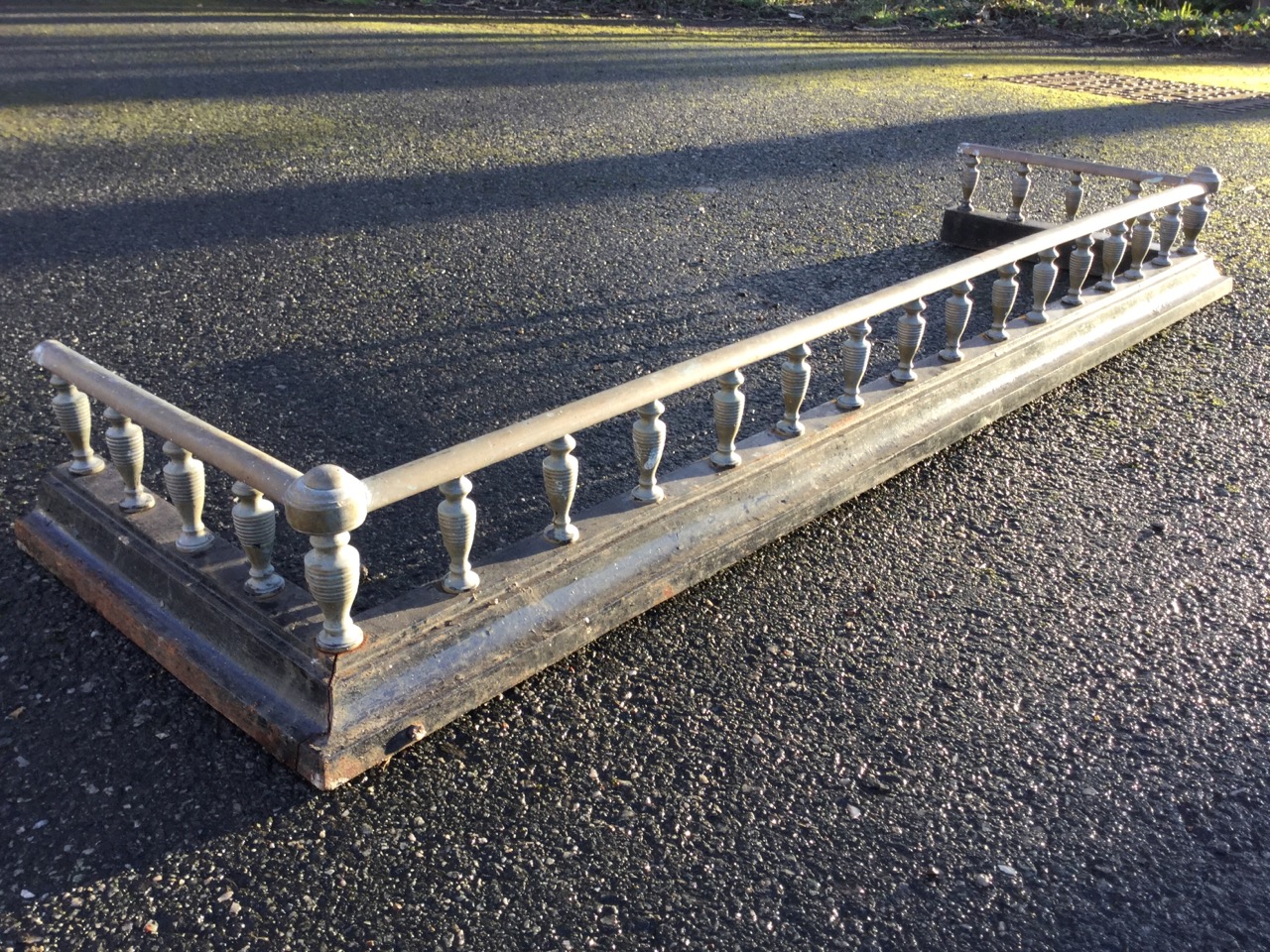 A Victorian brass and cast iron fender, with rows of ribbed gallery spindles supporting rail, raised