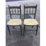 A pair of stained rush seated chairs, the backs with turned gallery spindles, supported on turned
